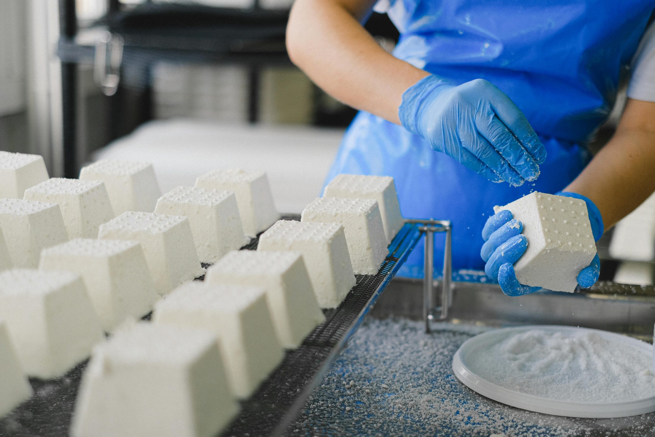 Worker making ricotta cheese in a food factory with precise technique.
